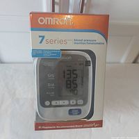 Front view of the Omron 7 Series BP760CAN blood pressure monitor in sealed box showing product image and branding.
