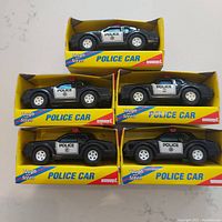 Five Buddy L Brute Police Cars in original yellow packaging arranged on surface