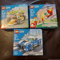 Three sealed Lego City sets laid out showing front of boxes: 60322 (46 pcs), 60318 (53 pcs), 60312 (94 pcs).