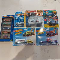 Photo of all nine Hot Wheels diecast vehicles in original packaging including the Web Racers 5-pack, Track Stars trucks, racing cars including Shelby GT 500, NASCAR car and Sunoco Diamond car.