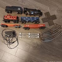 Complete train set including locomotive, 4 cars, multiple tracks, transformer shown spread on floor