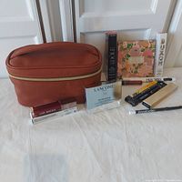 Photo of brown makeup bag and all boxed or packaged cosmetic items arranged around it
