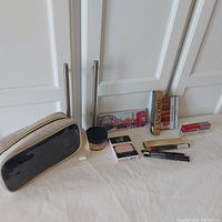 Makeup bag and assorted boxed makeup items laid out on white surface