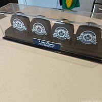 Full view of four elite collector hockey pucks each mounted in a clear display case with black base and commemorative label.