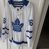 Full front view of white Toronto Maple Leafs hockey jersey with Mitchell Marner #16 logo and blue accents.