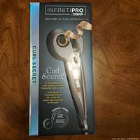 Front of the box showing branding, image of device with a curl strand, titanium ceramic logo