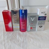 Photo showing five boxed skincare serums standing upright on a white cloth background. Boxes display brand names and product details clearly.