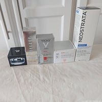 Photo showing five boxed skincare products standing next to each other on a white surface against a door background.