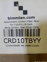 Label showing Bimmian branding for AutoCarbon Carbon Fiber Rear Lip for F10/F11 M-Tech model, black carbon fiber, dual exhaust compatible.