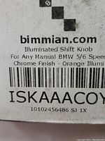 Label showing bimmian.com branding and product details: Illuminated Shift Knob for any manual BMW 5/6 speed, chrome finish, orange illumination
