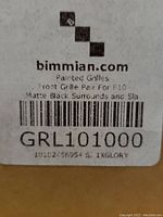 Label on packaging showing Painted Front Grille Pair for BMW F10 with matte black surrounds and slats, part number GRL101000 by bimmian.com.