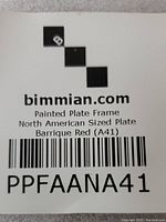 Close-up of label showing brand bimmian.com, product as Painted Plate Frame, North American Sized Plate, color Barrique Red (A41).