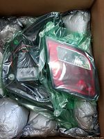 Pair of BMW tail lamps in plastic packaging inside box with padded packaging.