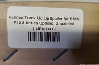 Close up of the label on packaging indicating the product is a Painted Trunk Lid Lip Spoiler for BMW F10 5 Series with option unpainted and SKU LIP101XXX