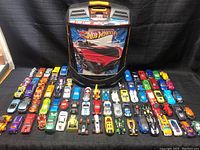 Full view of all die-cast cars laid out in rows with Hot Wheels storage case behind them