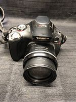 Front view of Canon PowerShot SX30 IS camera showing lens and top controls.