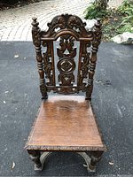 Front view of the vintage wooden chair showing detailed Gothic carving on the backrest and seat.