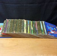 Side view of 35 colorful hardcover children's Disney books arranged in a row showing decorated spines
