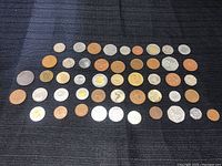 Full display of all 44 assorted coins laid out on a dark cloth background.