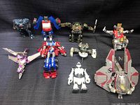 Top view of 8 assorted Transformers toys on black fabric background
