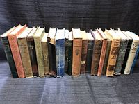 Front view of all 17 vintage books lined up side by side, showing a variety of spine colors and title fonts.
