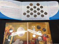 Top view of three different coin sets laid out, including the Olympic-themed coins and colorful packaging with wrapped gifts.