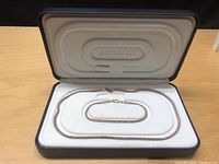 Silver necklace and bracelet set displayed neatly in a jewelry case showing the chain links and clasps.