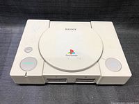 Top view of Sony PlayStation console showing logo and power/open/reset buttons.