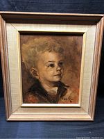 Full view of the framed oil painting showing the child portrait and frame.