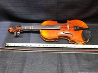 Violin laid flat with two bows and measuring tape
