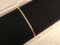 Gold bracelet chain displayed on black velvet bracelet form