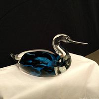 Side view of signed glass bird sculpture showing sapphire blue interior and delicate beak.