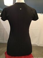 Back of black short sleeved athletic shirt on mannequin showing Lululemon logo