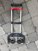 Folding Magna Cart hand truck fully collapsed to show compact storage size and dual wheels.
