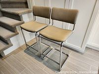 Two Mid-Century Modern chairs placed side-by-side showing taupe vinyl upholstery and chrome frames
