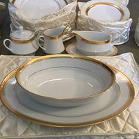 Front view showing dinner plate with soup bowl stacked, cream pitcher, sugar bowl, gravy boat and plates behind