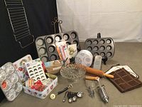 Wide shot showing entire lot including muffin pans, rolling pins, cake stand, cookie cutters, tin box, oven mitt, and other kitchen tools.