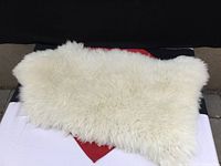 Full view of white sheep skin rug showing thick fluffy fur texture and irregular natural shape.