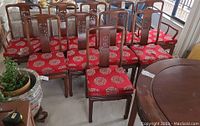Ten rosewood dining chairs with red upholstered seats arranged in two rows