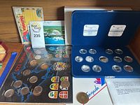 Coins displayed in blue velvet case alongside Canadian coin map display and postcards