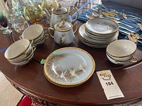 Wide view of full tea set including tea cups, saucers, plates, teapot, and sugar bowl with delicate crane and gold detailing.