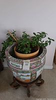 Overview showing porcelain planter holding jade plant in inner pot on wooden stand