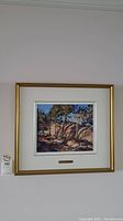 Full frontal view of gold framed painting hung on wall with auction tag visible