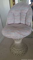 Side view of white rattan chair with cushioned seat and backrest in pastel camouflage pattern.