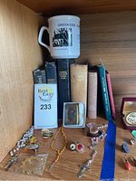 Photo of religious books, rosaries, jewelry and a coffee mug on a wooden shelf