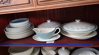 Full view of set in cabinet showing stacked plates, covered serving dishes, and gravy boat.