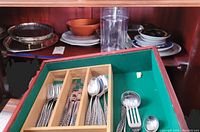 Photo showing flatware including forks, knives, and spoons in a green-felted wooden organizer, along with additional serving utensils and forks on the side