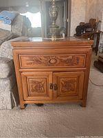 Full front view of one table placed beside sofa showing drawer and cabinet with dragon carvings