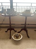 Two wooden Bombay Company tables placed side by side near window; octagonal tops, tripod bases, dark wood finish.