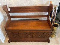 Front view of carved wood bench with umbrella stand and contents